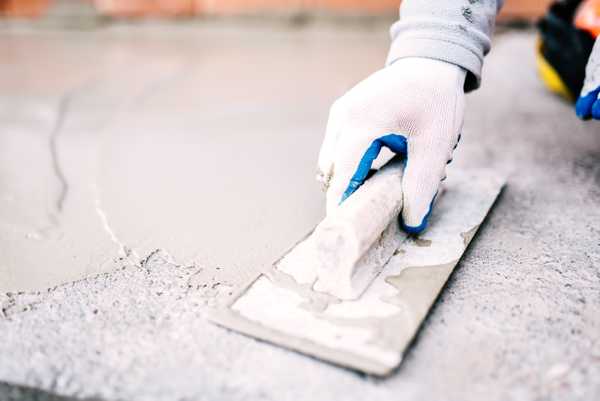 Industrial worker on construction site laying sealant for waterproofing cement.